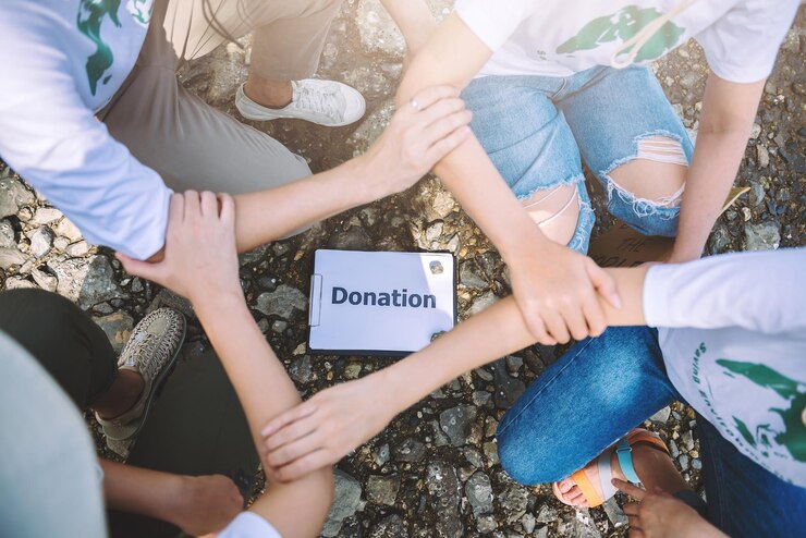 Team of volunteers holding hands around a "Donation" sign, demonstrating NSW charitable fundraising collaboration.