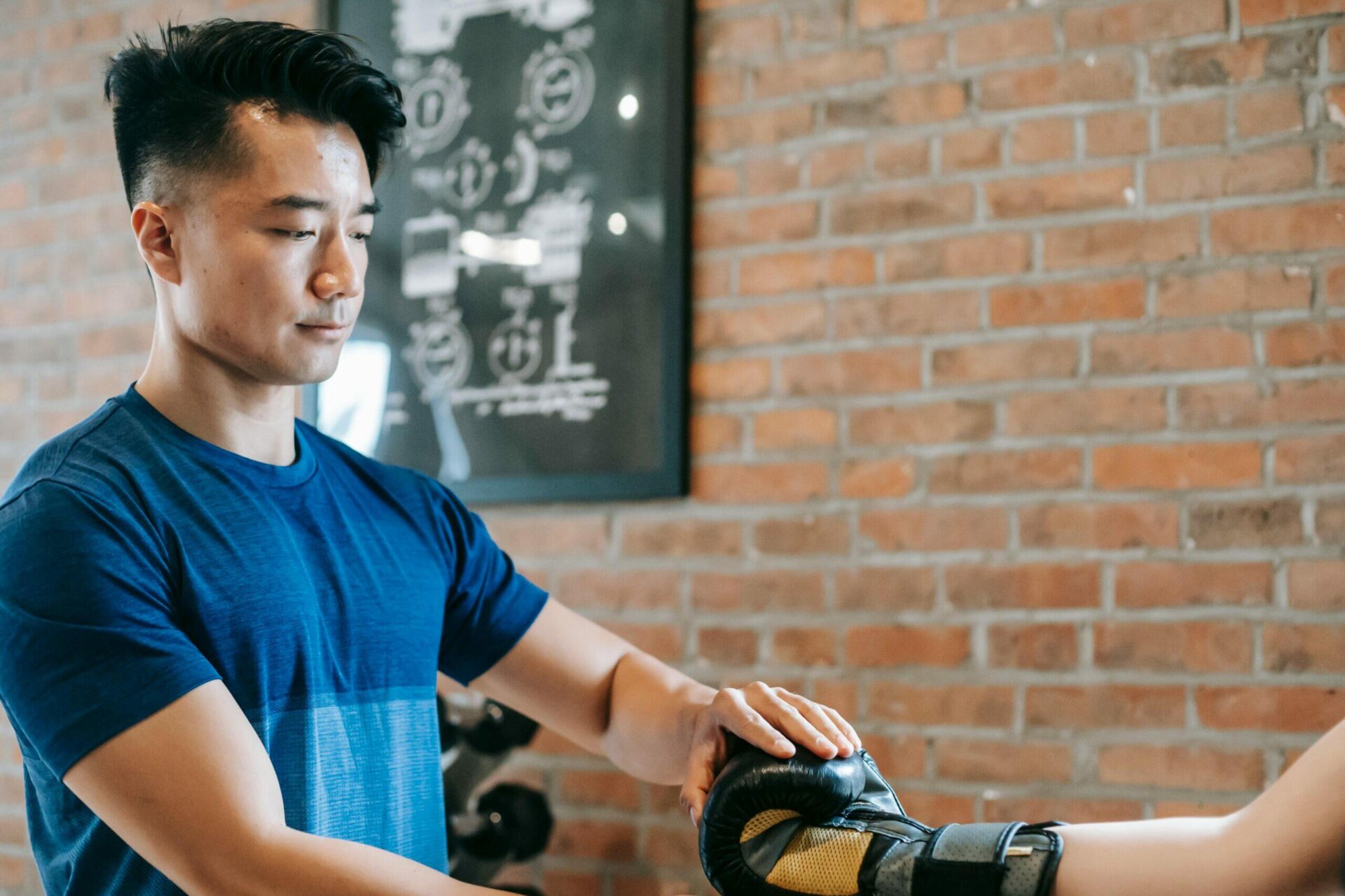 Man helping someone put on boxing gloves.