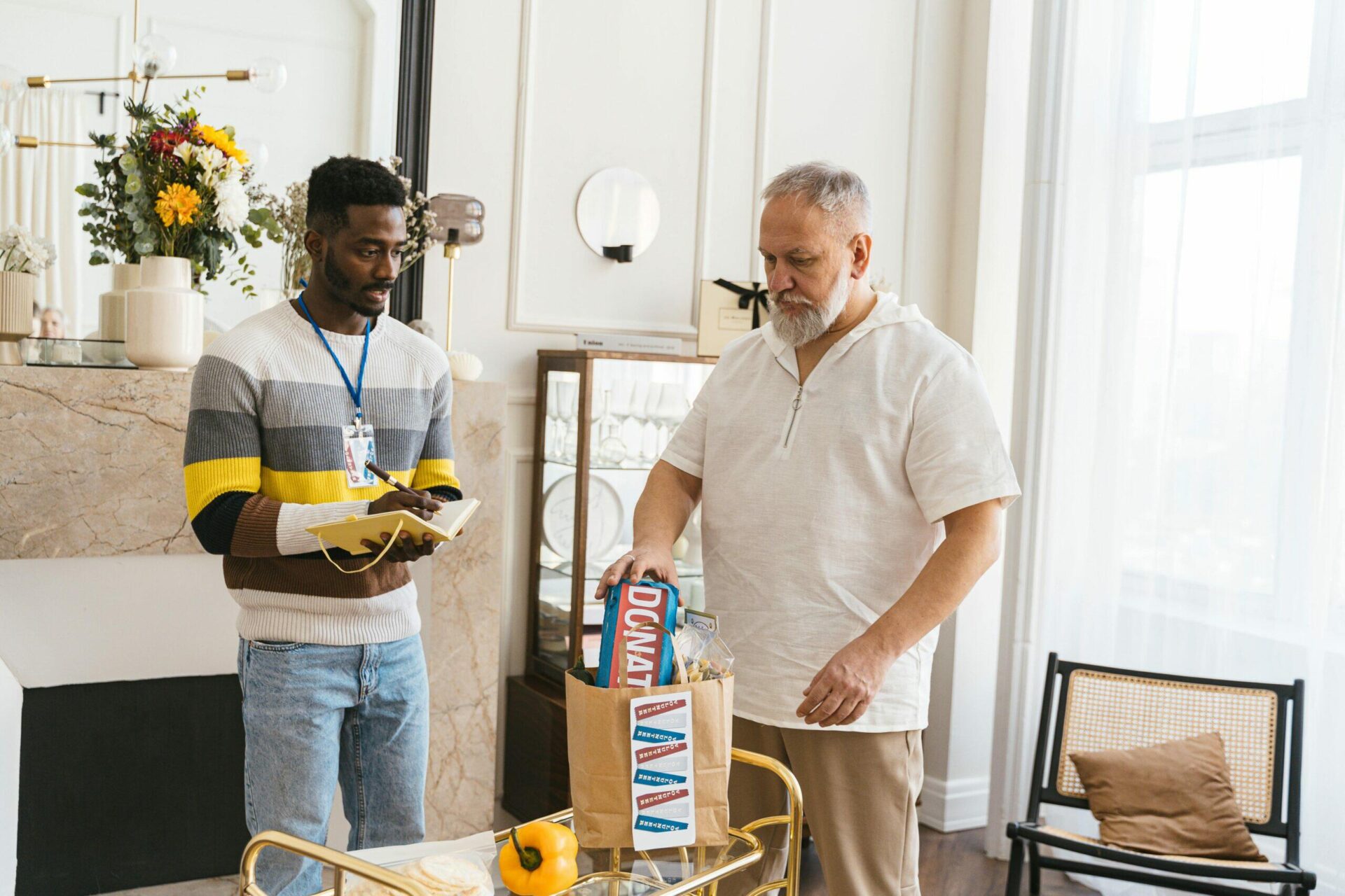 Two men reviewing a donation of food at a charity. "Donate" is visible on the box.