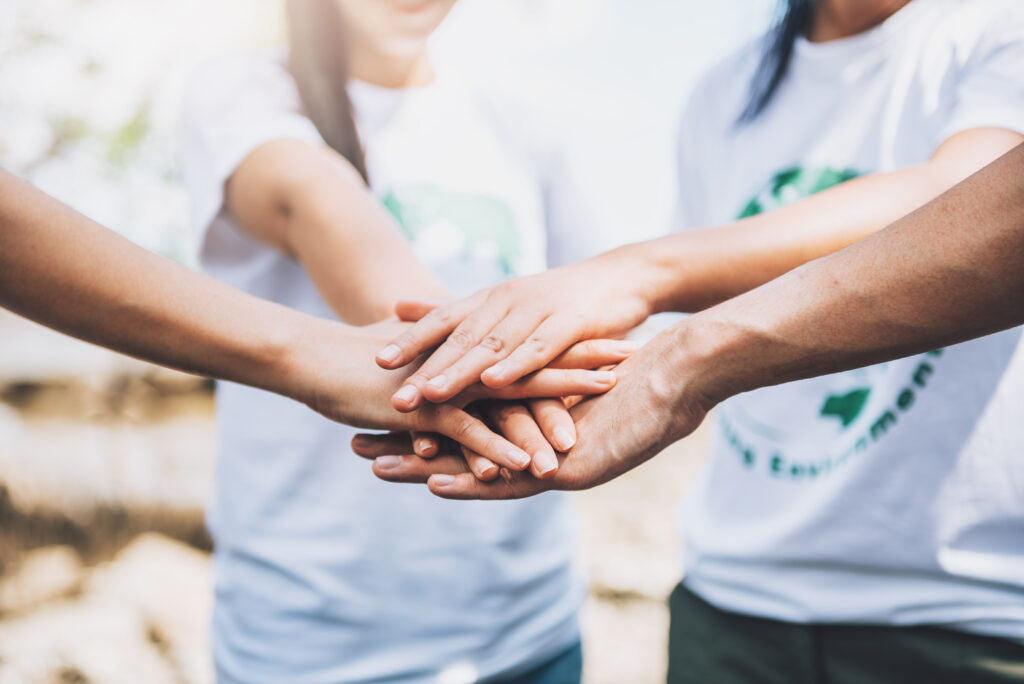 Team of volunteers stacking hands, showing unity and collaboration.