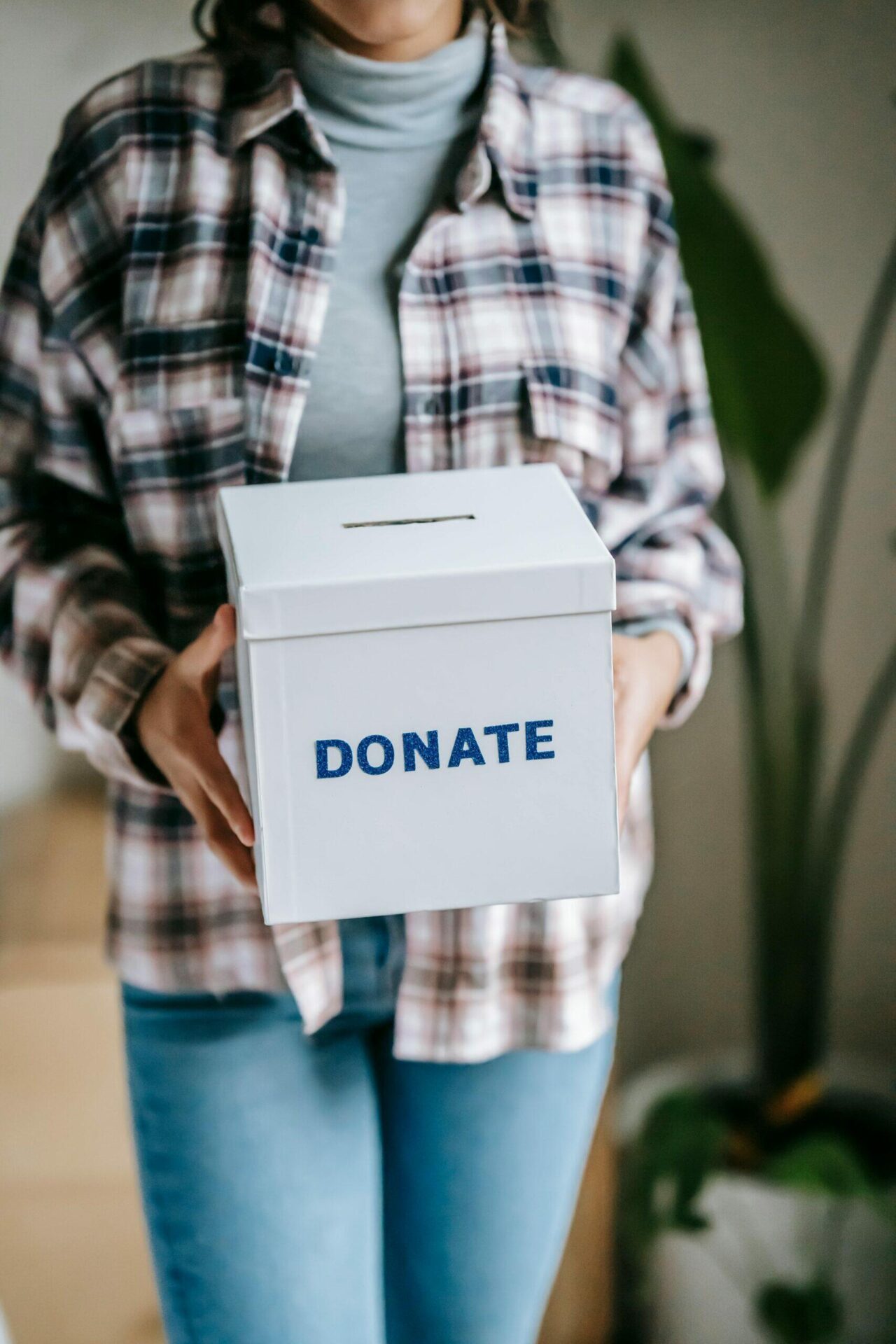 Person holding a donation box labeled "DONATE".