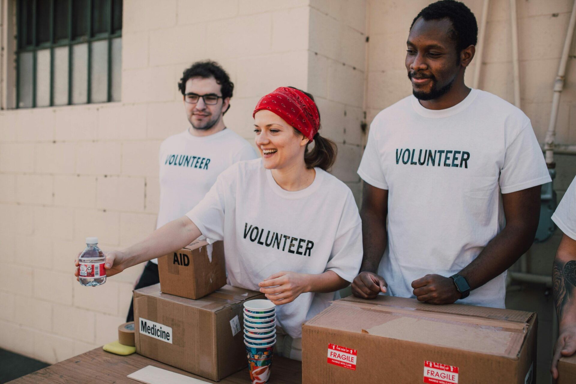 Volunteers sorting donations for charity, boxes labeled "Aid" and "Medicine," demonstrating accountability and governance.