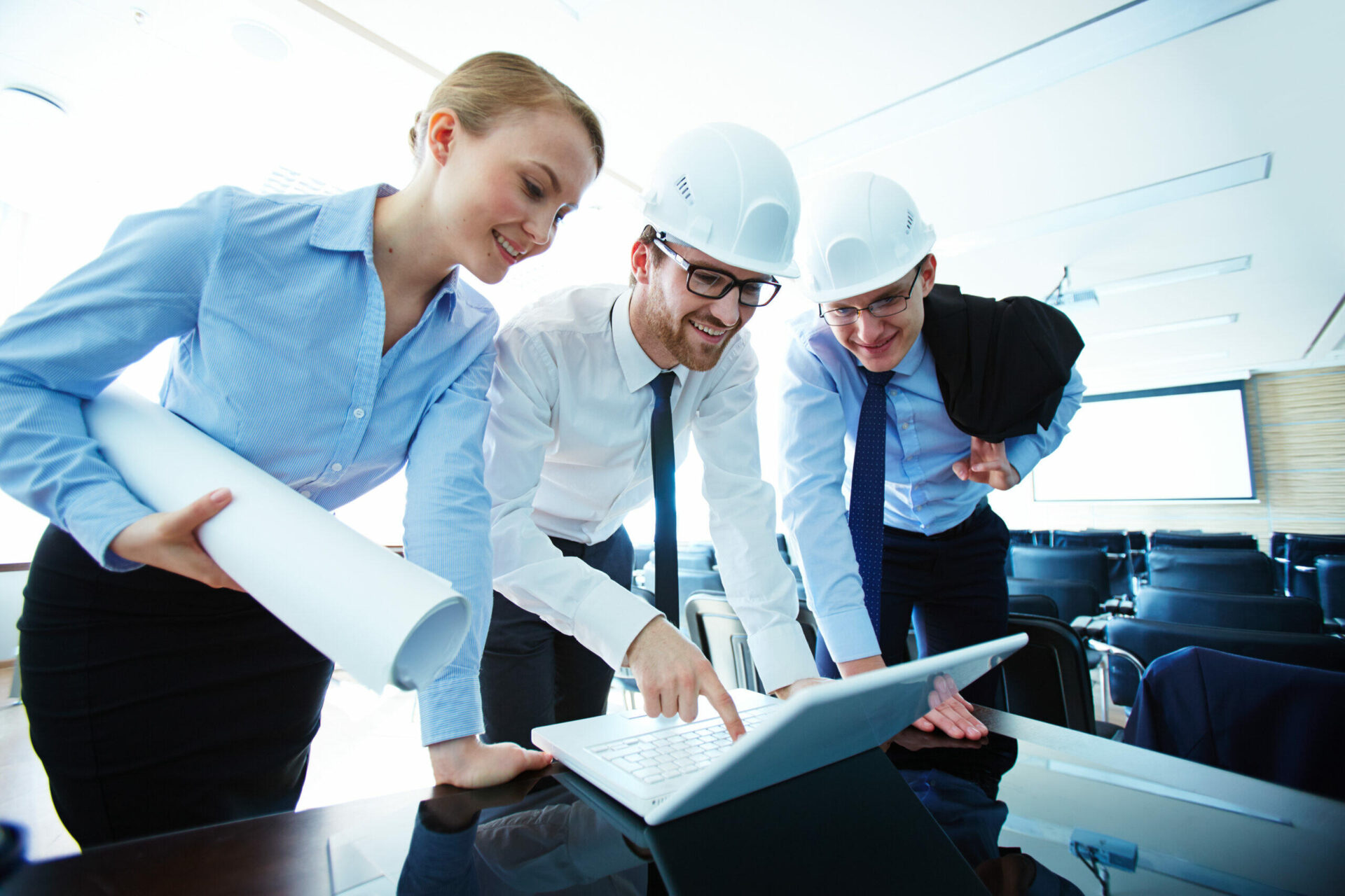 Team of architects and engineers reviewing plans on a laptop.