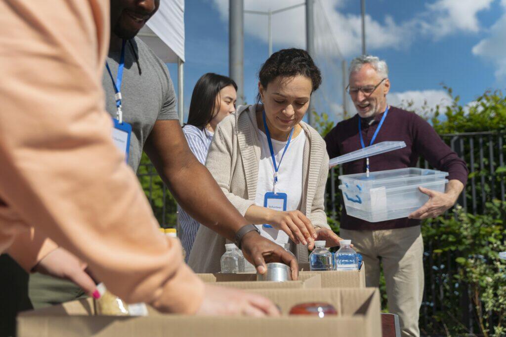 Volunteers sorting donations at a charity event. One volunteer's name tag reads "Volunteer".