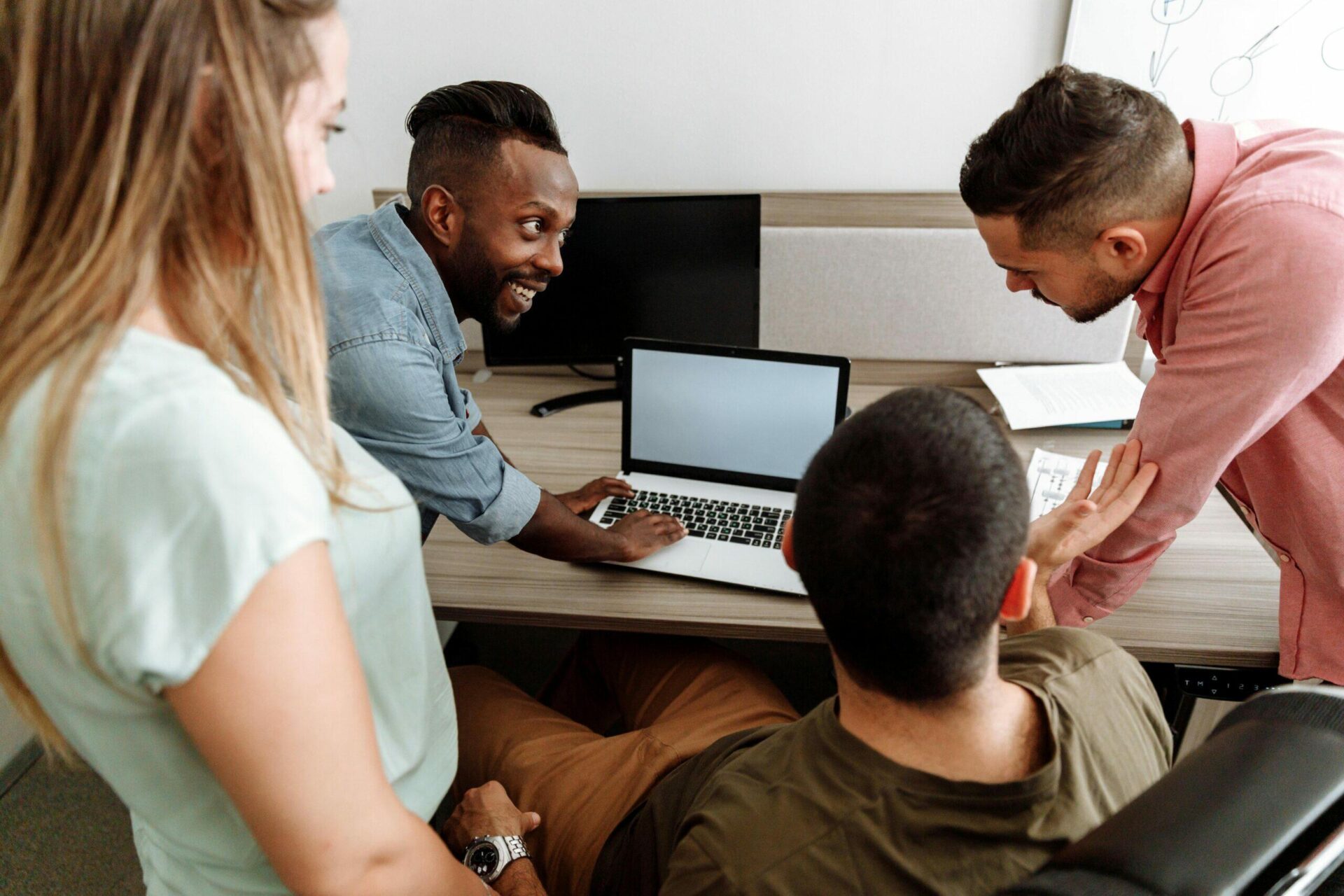 Diverse team collaborating on laptop, discussing nonprofit board member compensation.