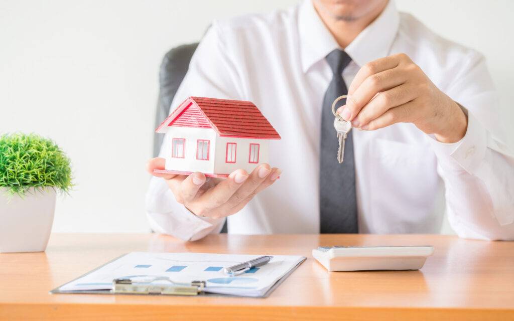 Real estate agent handing over house keys and model home