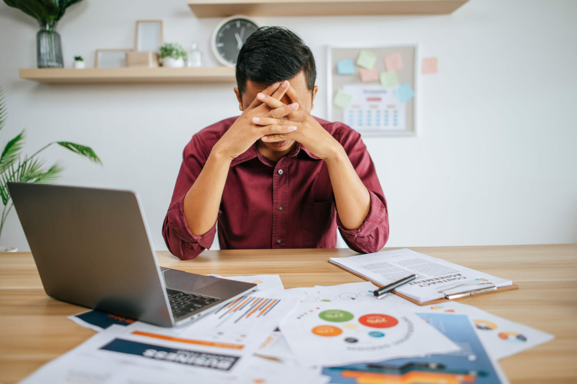 Stressed man at desk with laptop and financial documents