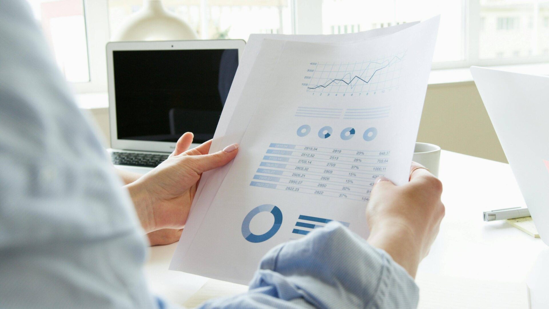 Person analyzing financial charts and data on a document.