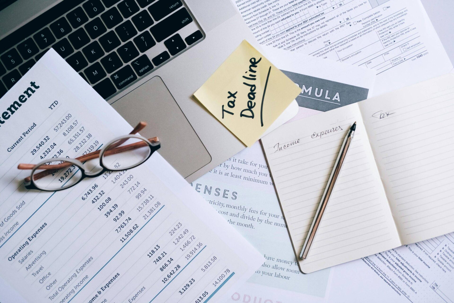 Tax deadline paperwork with "Tax Deadline" sticky note, tax forms, and financial documents.