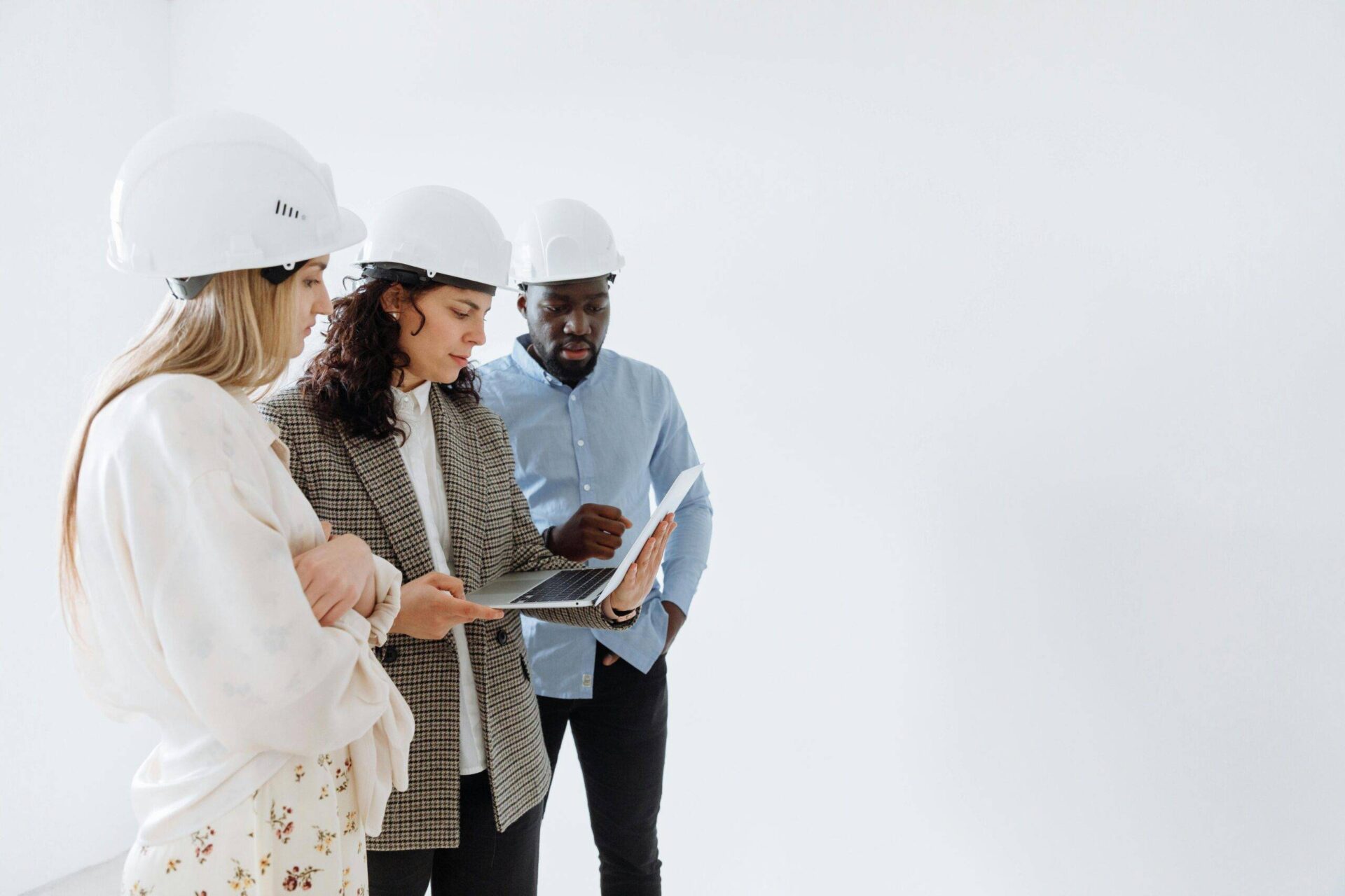 Property developers reviewing contracts on laptop. NSW construction team in hard hats.