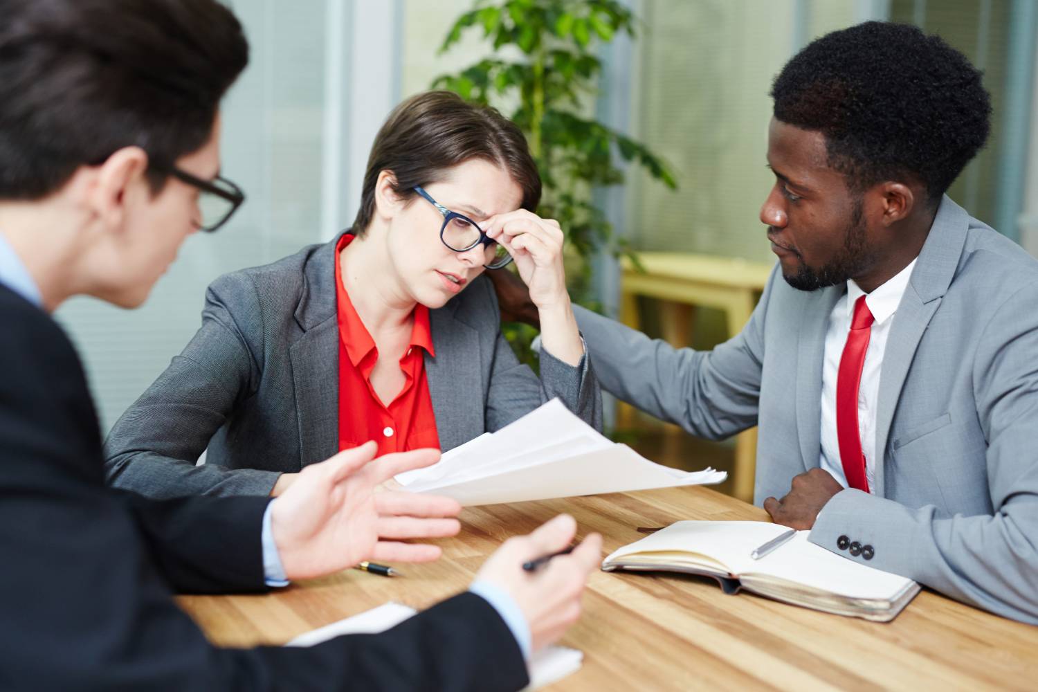 Concerned business colleagues reviewing documents at a meeting, one comforting another.