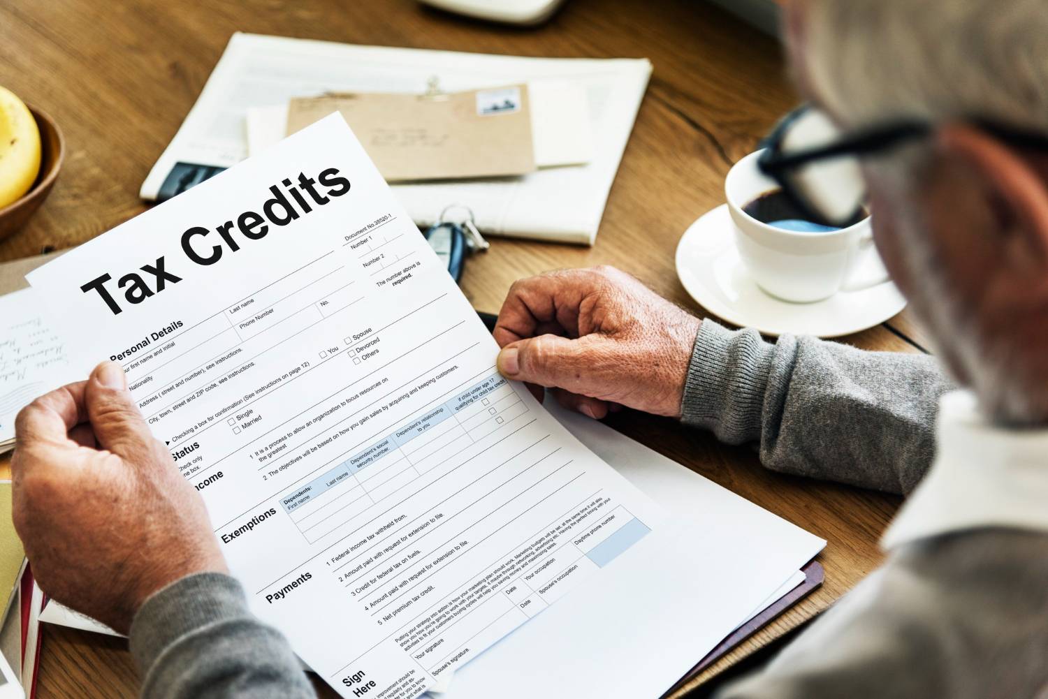 Senior man reviewing a "Tax Credits" form, potentially related to ATO & ACNC actions on tax concessions.
