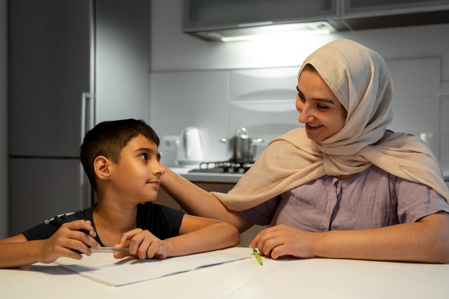 Mother in hijab helping her son with homework. Understanding Islamic Law.