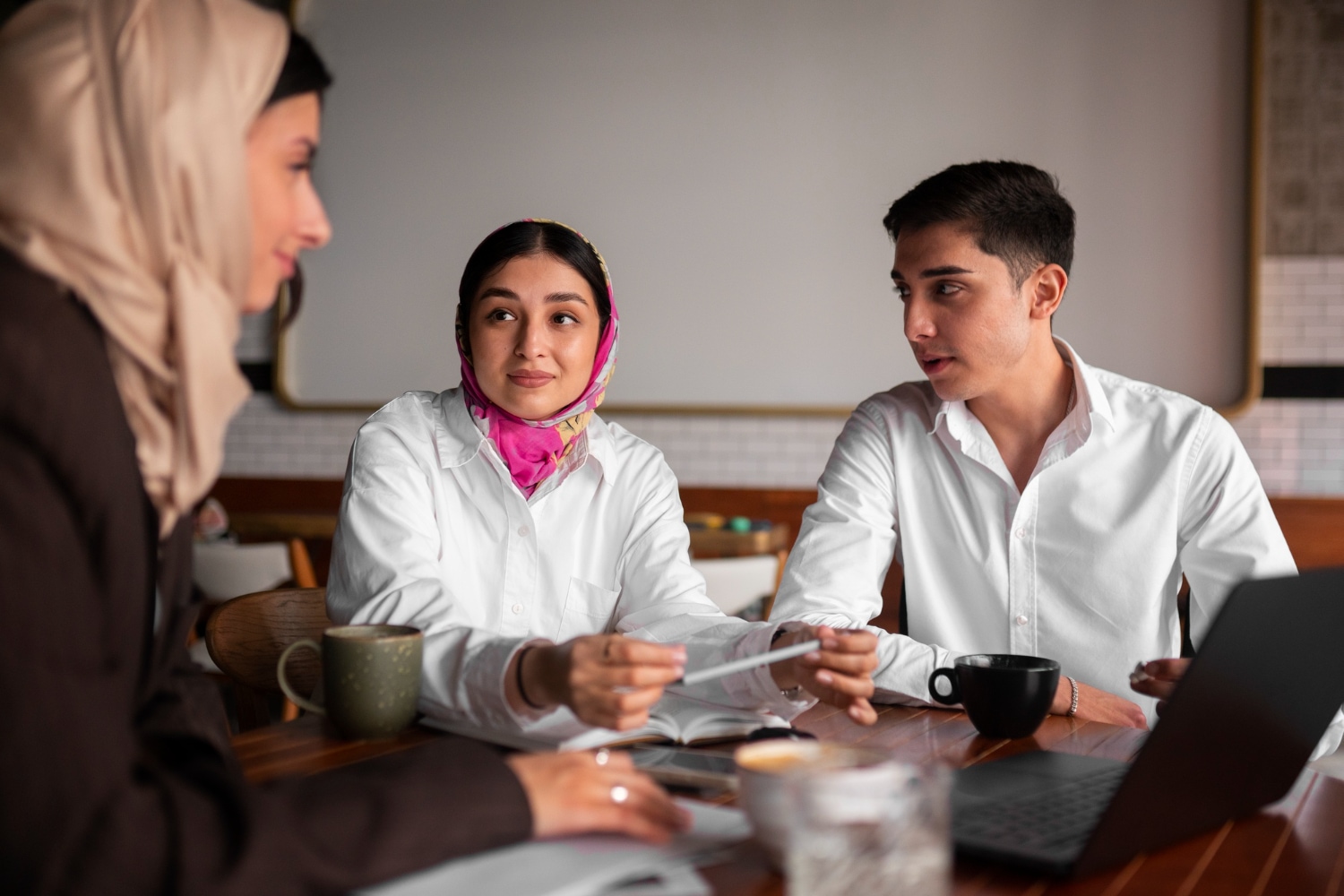 Islamic will planning meeting: Three people at a table with a laptop and coffee.
