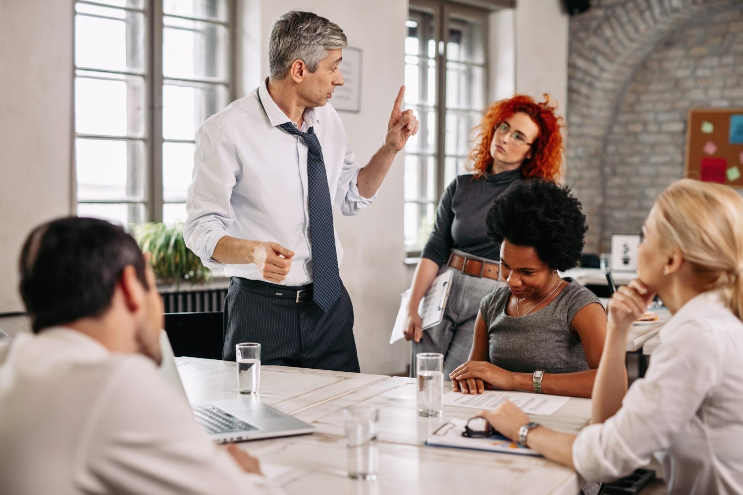Frustrated manager lecturing employees in a meeting. Workplace conflict.