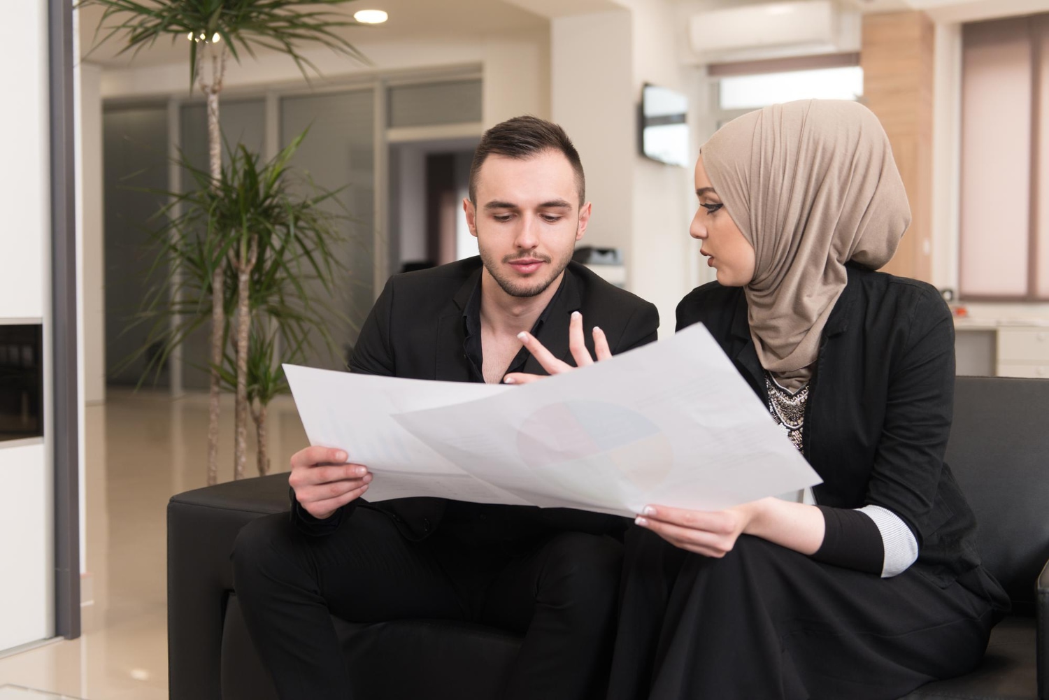 Business colleagues, one wearing a hijab, reviewing documents. Estate dispute resolution concept.