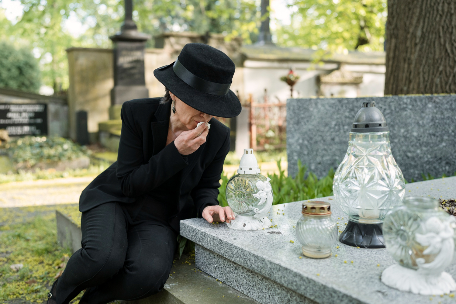 Woman in black at gravesite with lanterns, contemplating death gifts.