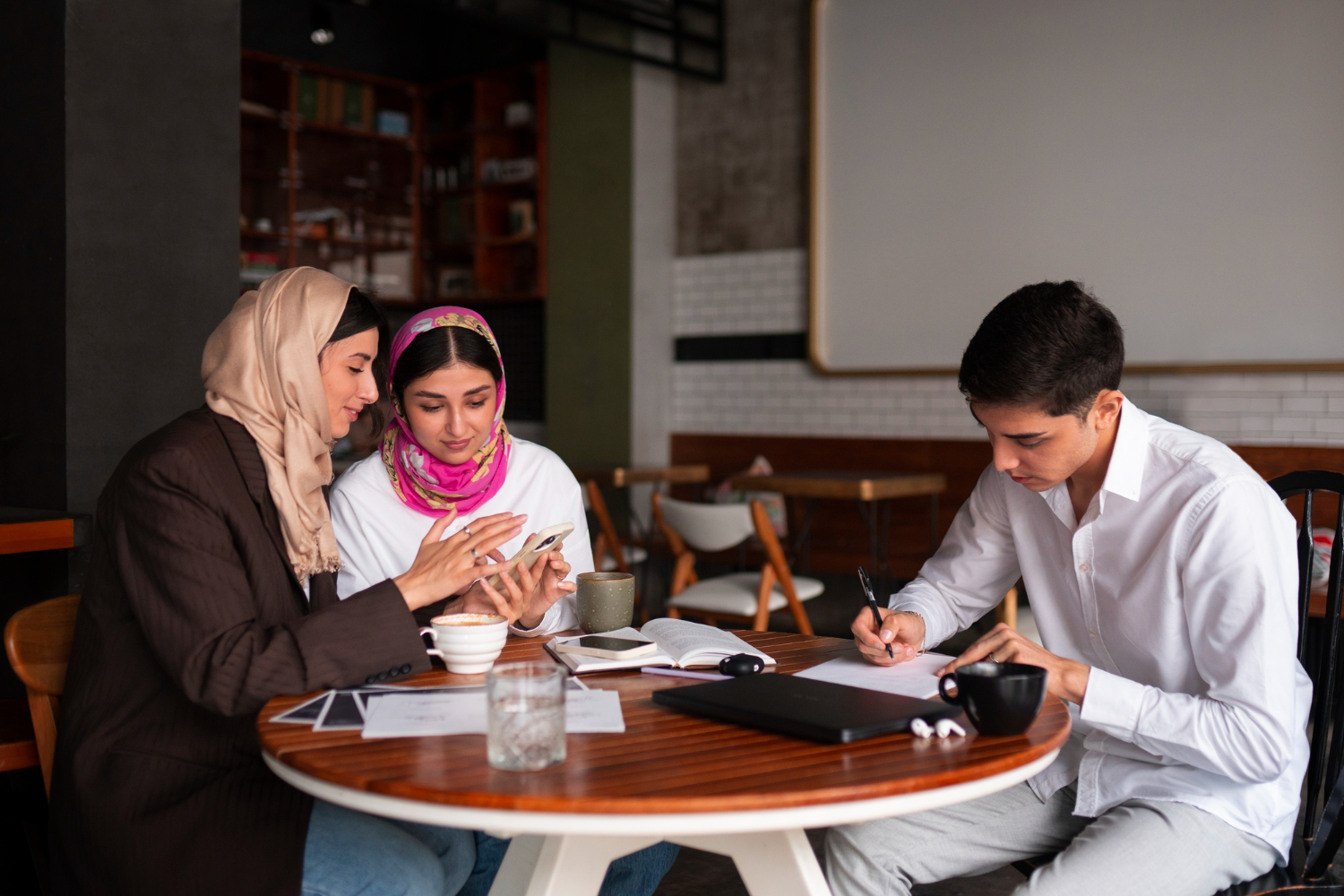 Three young people discussing Islamic inheritance certificates at a table.