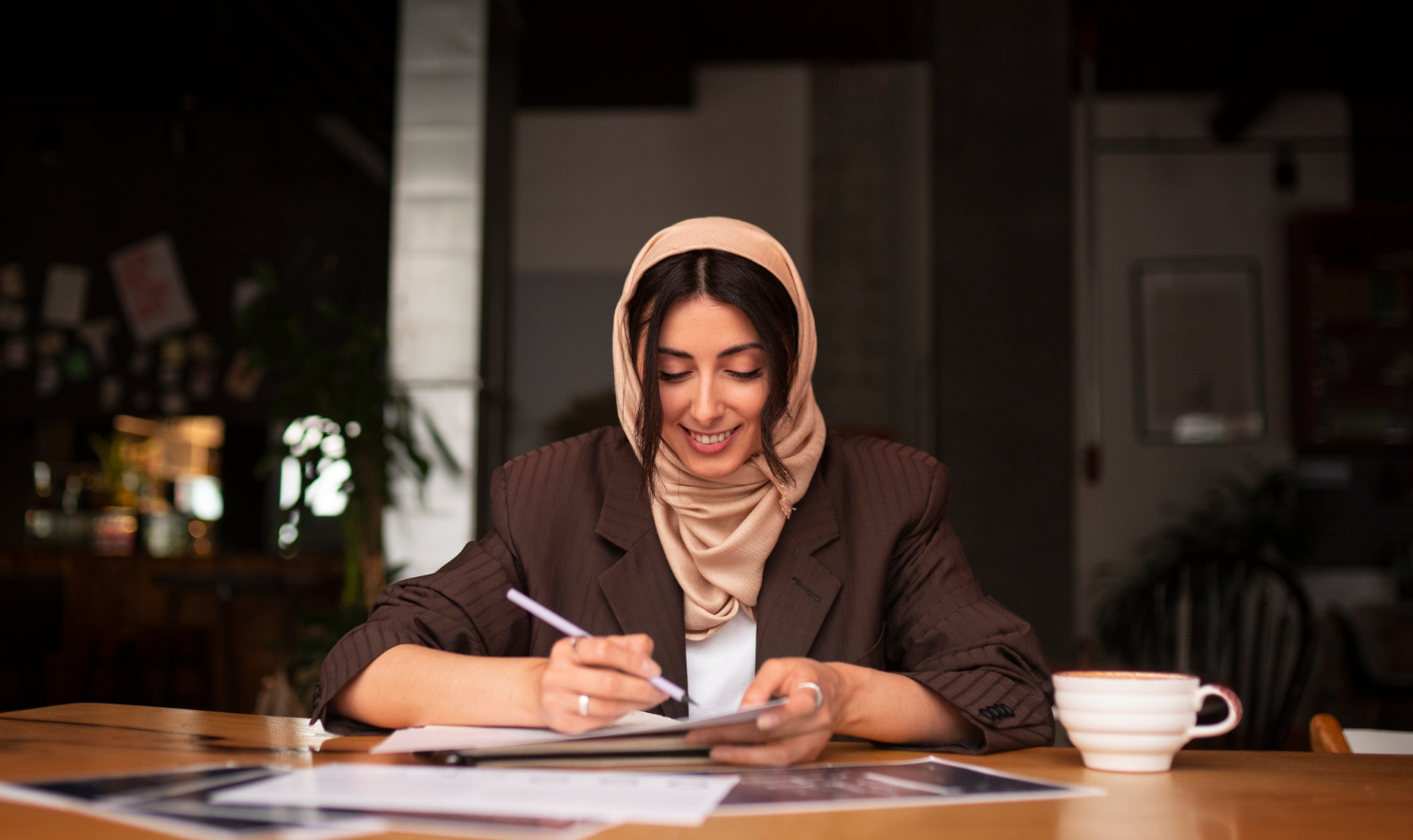 Woman in hijab reviewing documents at a table, discussing Zakat and debt management.