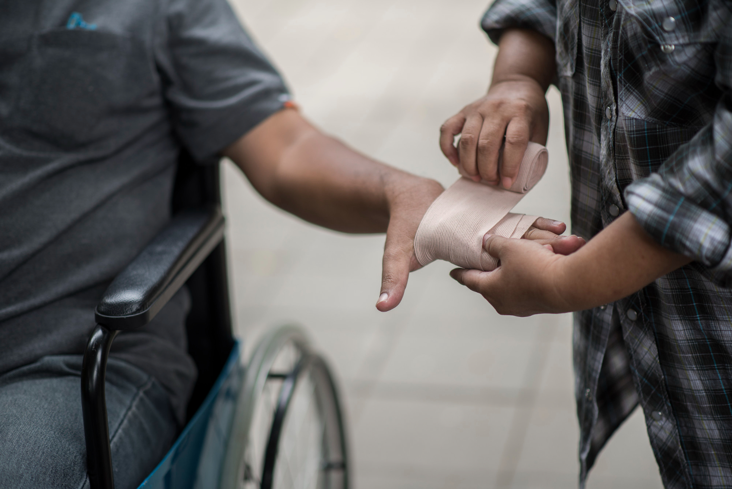 Person in wheelchair receives hand bandage, illustrating NFP negligence and injury management.
