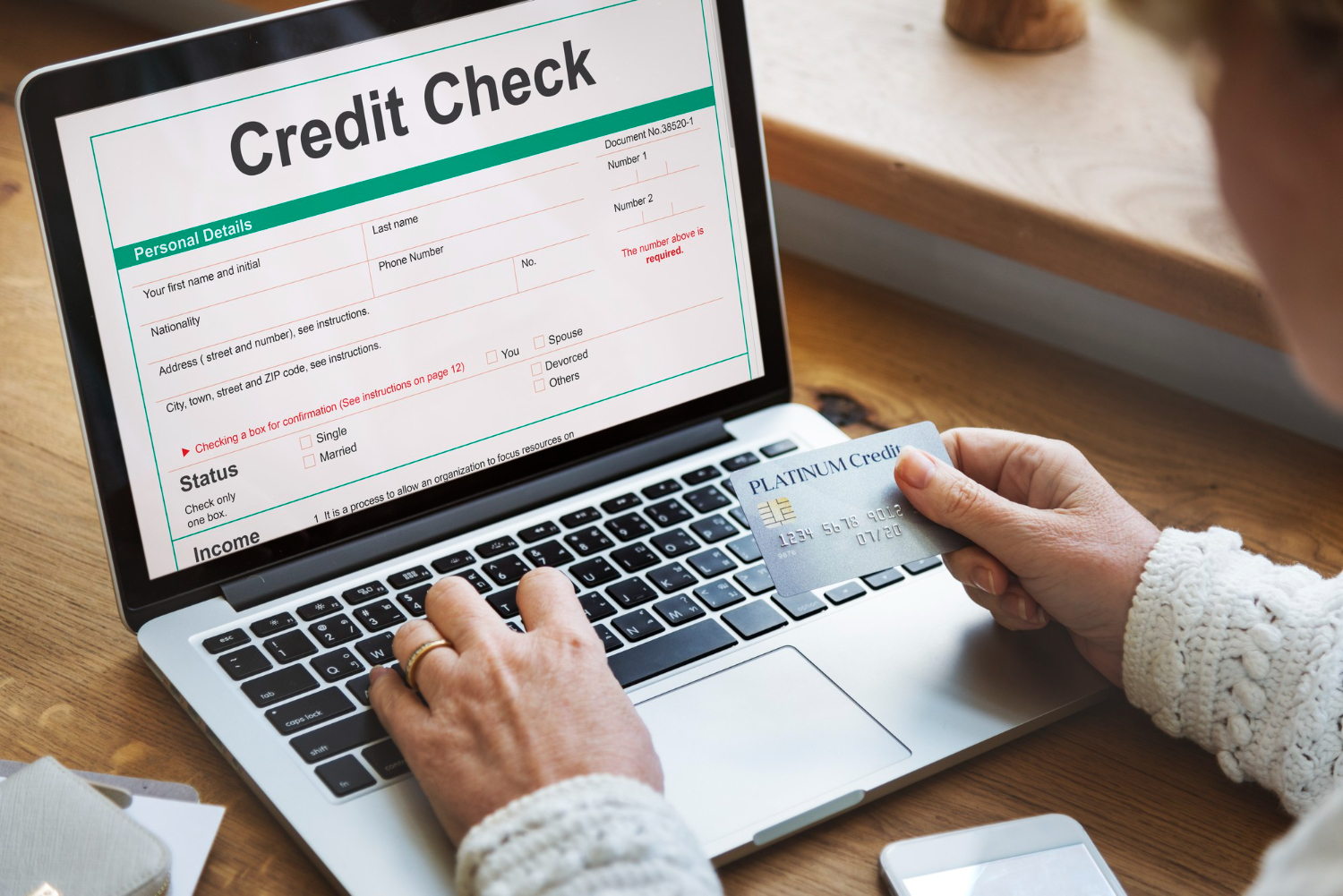 Person filling out credit check form online, holding a credit card