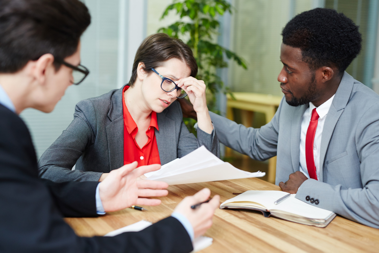 Business meeting discussing probate applications in NSW, with a stressed woman and supportive colleagues.