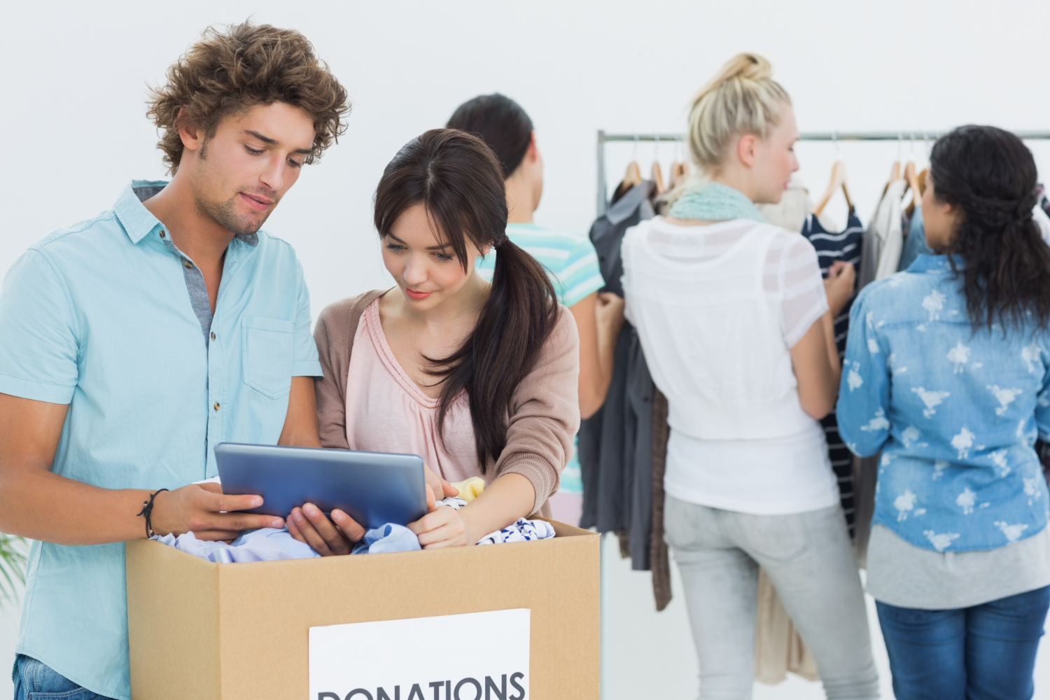 Volunteers sort donations for a community charity, with a box labeled "DONATIONS" in the foreground.