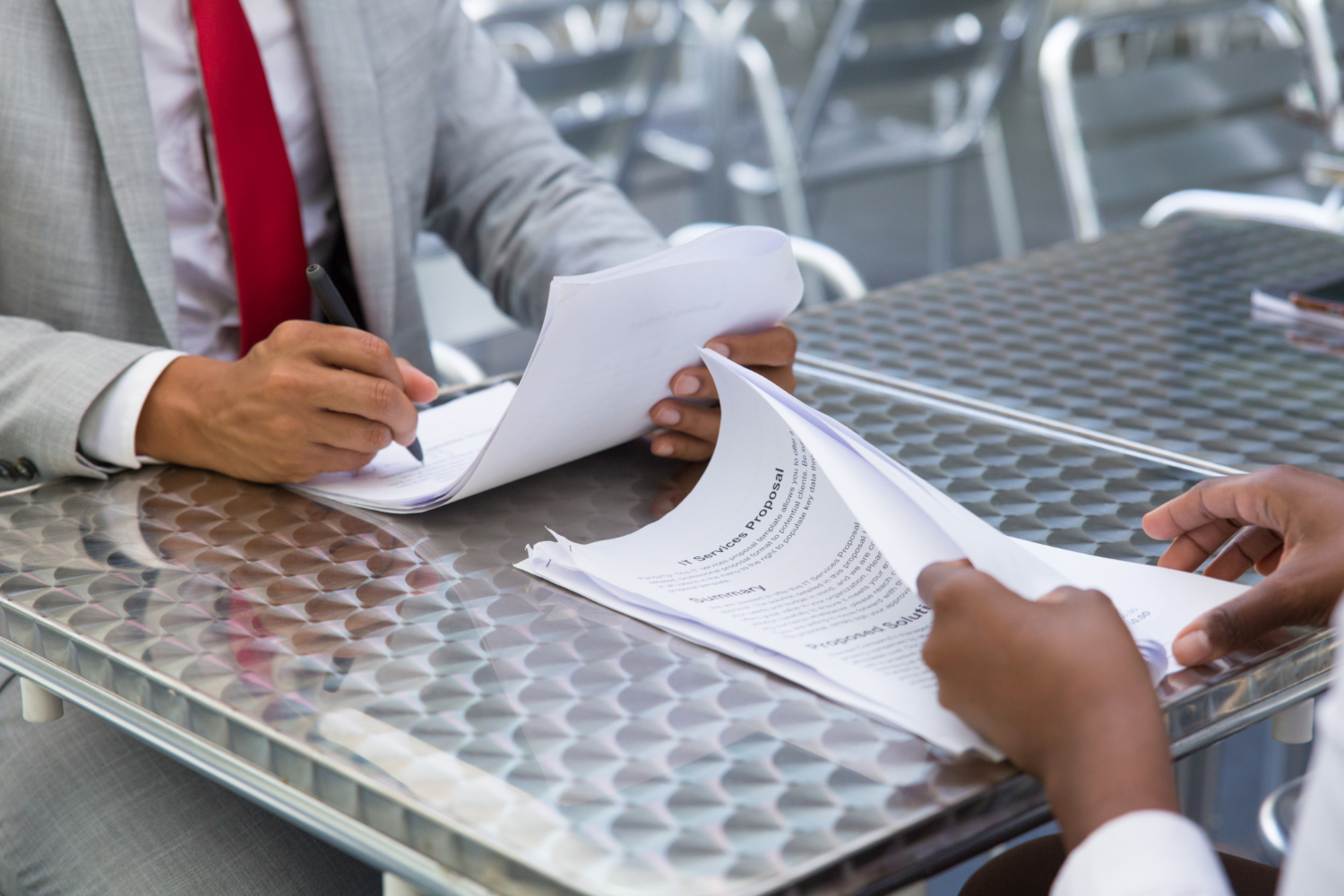 Two people reviewing legal documents, one signing, at a table.