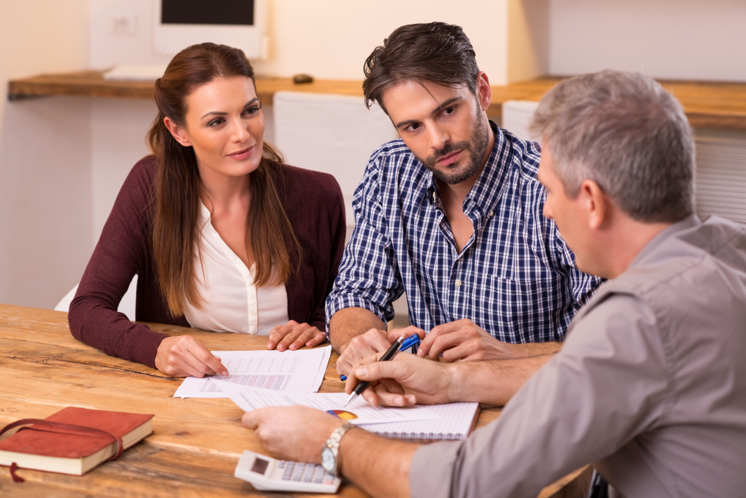 Three people discussing legal documents at a table, possibly estate distribution.