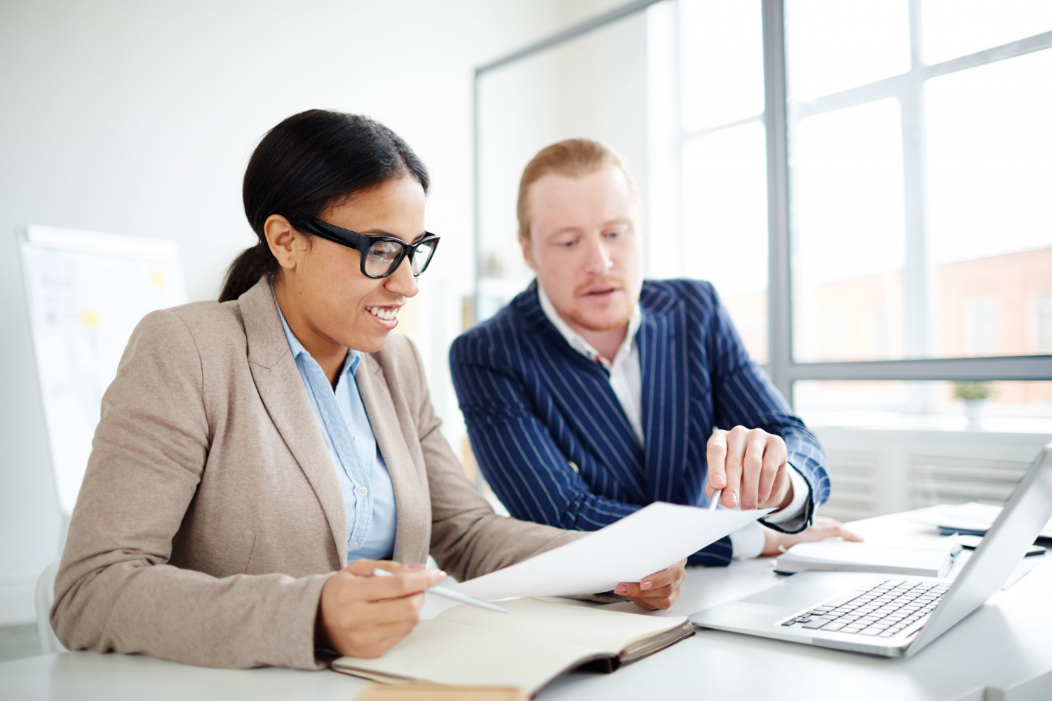 Two professionals discussing legal documents at a desk, one pointing.