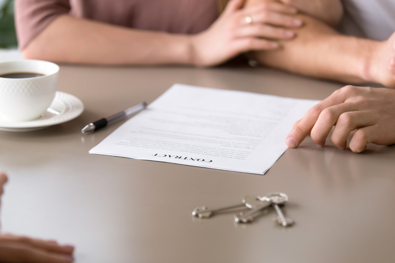 Hands signing a contract, keys and coffee on table, deceased estate NSW