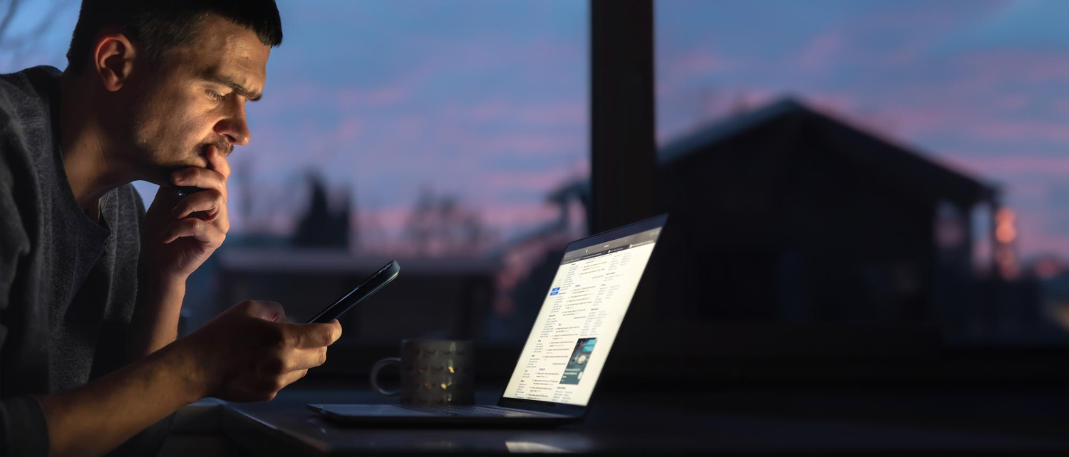 Man looking at smartphone and laptop, contemplating digital assets after death.